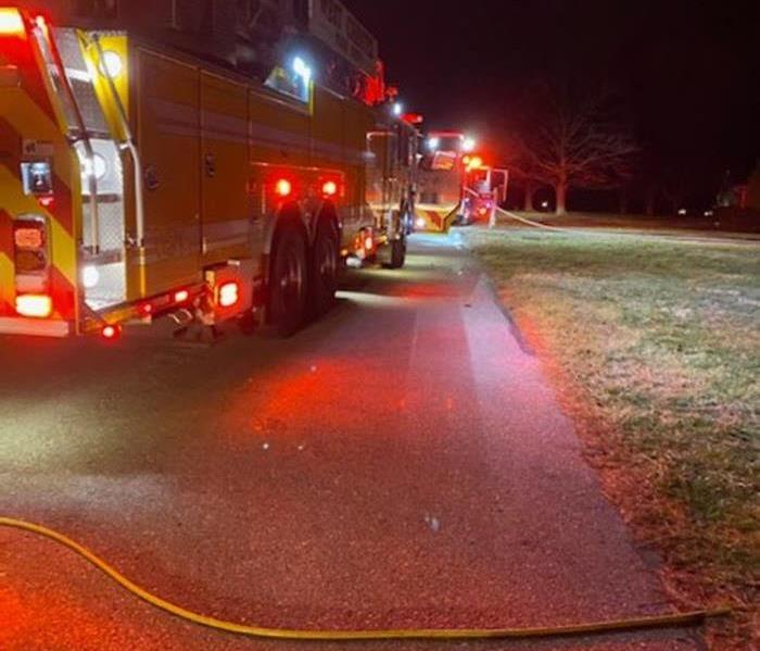 fire engines at nite parked with hoses from the trucks going across a lawn