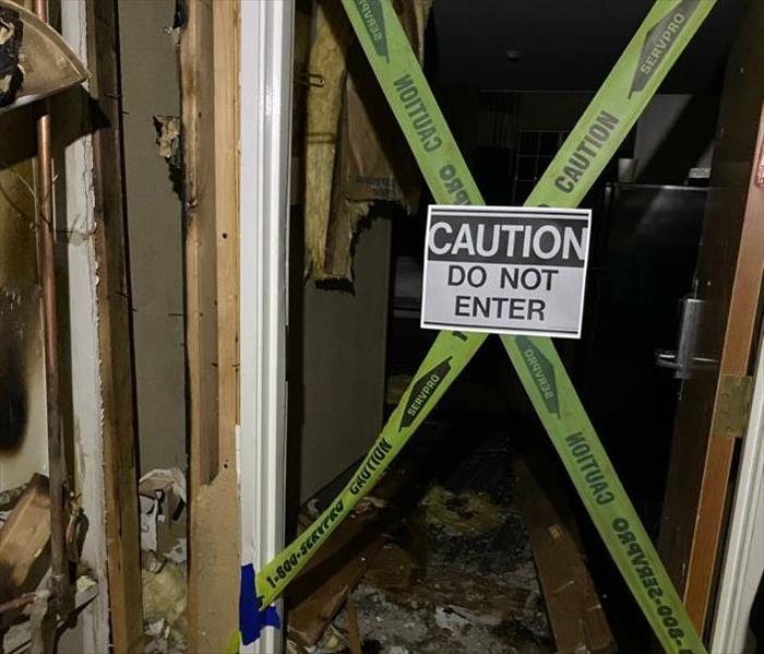 fire damaged room with do not enter sign and tape blocking door