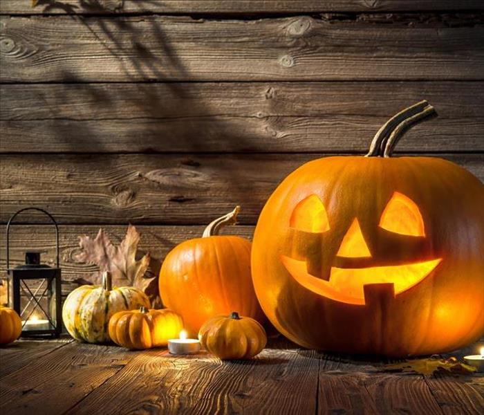 A jack-o-lantern, pumpkins, gourds, and a lantern make up a lovely halloween display. 